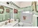 Traditional bathroom features green wallpaper, shower-tub combo, and vanity at 3923 Manor Oaks Ct, Leesburg, FL 34748