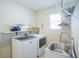 Bright laundry room with front loading machines, practical shelving and sink basin at 5429 Sw 44Th Court Rd, Ocala, FL 34474