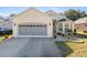 Tan one-story house with gray garage door, landscaping, and walkway at 6760 Sw 112Th St, Ocala, FL 34476