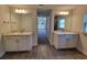 Bathroom with dual sinks, granite countertops, white cabinetry, and wood-look tile flooring at 6915 Sw 152Nd St, Ocala, FL 34473