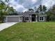 Charming single-story home with manicured lawn, a two-car garage, and mature trees in the background at 6915 Sw 152Nd St, Ocala, FL 34473