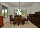 Formal dining area featuring wood furniture, decorative chairs, and bright natural light from the large window at 7387 Sw 99Th Ct, Ocala, FL 34481