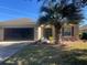 Home's exterior with a well-maintained lawn, a mature palm tree, and a screened-in two-car garage at 7387 Sw 99Th Ct, Ocala, FL 34481