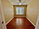 This empty room is equipped with hardwood floors, a ceiling fan, and a window at 7387 Sw 99Th Ct, Ocala, FL 34481