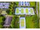 Aerial view showcasing multiple tennis courts with blue surfaces surrounded by lush green landscaping, ideal for recreation at 7387 Sw 99Th Ct, Ocala, FL 34481