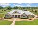 Aerial view of a luxurious ranch-style home with a metal roof, stone accents, and expansive green pastures at 12000 S Highway 475, Ocala, FL 34480