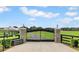 Ornate black metal entrance gate with stone pillars leading to a charming home and lush green landscape at 12000 S Highway 475, Ocala, FL 34480