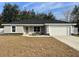 Newly constructed one-story home with gray exterior, white garage door, and landscaping at 14351 Se 34Th Ct, Summerfield, FL 34491