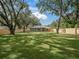Large, enclosed backyard showcasing a well-maintained lawn, mature trees, and a view of the home's exterior at 205 Brevard Ave, Lady Lake, FL 32159