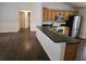 Open kitchen view showcasing wood cabinets, a breakfast bar, stainless steel appliances, and laminate flooring at 3752 Se 130Th St, Belleview, FL 34420