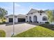 White house with three-car garage and a brick driveway at 5141 Greens Dr, Lady Lake, FL 32159