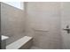 Modern shower with gray tiled walls, built-in seat, and grab bar for accessibility at 10322 Sw 99Th Ln, Ocala, FL 34481