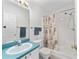 Well-lit bathroom featuring a shower-tub combo, vanity with a blue countertop, and decorative seashell shower curtain at 1112 Carvello Dr, The Villages, FL 32162