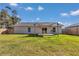 Backyard featuring a wood deck with sun shade, sliding glass doors, and a well-maintained lawn at 13787 Sw 43Rd Cir, Ocala, FL 34473