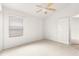 Cozy bedroom with a ceiling fan, window, and soft carpet flooring at 2418 Hopespring Loop, The Villages, FL 32162