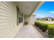 Inviting front porch featuring green shutters and trim complemented by lush landscaping on a sunny day at 2418 Hopespring Loop, The Villages, FL 32162