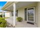 View of a covered front porch and entryway with green siding and shuttered windows at 2418 Hopespring Loop, The Villages, FL 32162