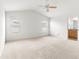 Spacious main bedroom featuring vaulted ceiling with ceiling fan, carpeted floors, and natural light from two windows at 2418 Hopespring Loop, The Villages, FL 32162