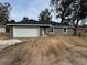 Newly constructed home with a gray exterior, white garage door, and landscaping to be completed at 3957 Se 137Th Ln, Summerfield, FL 34491