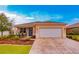 Tan house with white garage door, landscaping, and a brick driveway at 7838 Sw 85Th Cir, Ocala, FL 34481