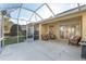 This screened patio boasts tile flooring, wicker furniture, and views of the landscaped backyard at 8535 Sw 82Nd Ter, Ocala, FL 34481