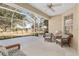 Enclosed patio with a ceiling fan and wicker chairs overlooks the lush, green lawn at 8535 Sw 82Nd Ter, Ocala, FL 34481