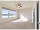 Sunlit bedroom featuring a large window with water view, neutral carpet, and a ceiling fan at 9858 Sw 75Th Street Rd, Ocala, FL 34481