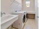 Bright laundry room featuring a washer, dryer, utility sink, counter space, and convenient storage shelf at 9858 Sw 75Th Street Rd, Ocala, FL 34481