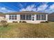 Exterior view of home featuring a sunroom surrounded by green lawn and manicured shrubbery at 9858 Sw 75Th Street Rd, Ocala, FL 34481