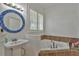 Bathroom with pedestal sink, jetted tub, and mosaic mirror at 10170 Se 106Th Ln, Belleview, FL 34420