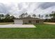 Rear exterior view of the home showcasing a well-maintained lawn and a serene backdrop of trees at 12217 Sw 67Th Ln, Ocala, FL 34481