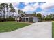 Side view of the home with a long driveway leading to an attached garage, set in a natural landscape at 12217 Sw 67Th Ln, Ocala, FL 34481