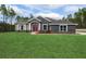 Charming single-story home featuring stone accents, a well-manicured lawn, and a striking red double-door entrance at 12217 Sw 67Th Ln, Ocala, FL 34481