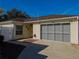 Tan one-story house with brown roof, gray garage door, and landscaped yard at 17074 Se 75Th Wickson Ct, The Villages, FL 32162