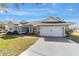 Gray house with white accents, two-car garage, and landscaped yard at 17470 Se 115Th Terrace Rd, Summerfield, FL 34491