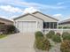 Tan house with white picket fence, two car garage, and screened porch at 1817 Hallandale Ln, The Villages, FL 32162