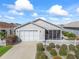 Tan house with white picket fence, two car garage, and screened porch at 1817 Hallandale Ln, The Villages, FL 32162