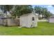 Tan storage shed with a wooden door in a grassy backyard at 6558 Se 9Th Pl, Ocala, FL 34472