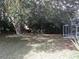 View of a backyard with a large tree, shrubs, and a screened enclosure at 7106 Sw 115Th Loop, Ocala, FL 34476