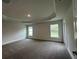 Spacious bedroom with a tray ceiling, neutral walls, plush carpet, and ample natural light at 77 Olive Dr, Ocala, FL 34472