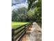 Gravel driveway lined by a rustic fence leading to a picturesque property with lush greenery and mature trees at 10245 Sw 105Th St, Ocala, FL 34481