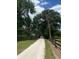 Gravel driveway lined by a rustic fence leading to a picturesque property with lush greenery and mature trees at 10245 Sw 105Th St, Ocala, FL 34481