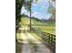 Long driveway leading to a private estate, bordered by a wooden fence and green pastures at 10245 Sw 105Th St, Ocala, FL 34481