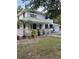 Charming two-story white home with a green roof, inviting front porch and well-maintained lawn at 10245 Sw 105Th St, Ocala, FL 34481
