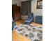 Comfortable living area with a blue arm chair, area rug with floral accents, and hardwood flooring at 10245 Sw 105Th St, Ocala, FL 34481