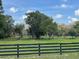 Serene pasture with mature trees and perimeter fence under a partly cloudy sky at 10245 Sw 105Th St, Ocala, FL 34481