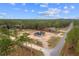 An aerial view shows the home on a large lot surrounded by trees and another home down the street at 11910 Sw 43Rd Street Road, Ocala, FL 34481