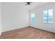 This spacious bedroom features wood-look flooring, a ceiling fan, and two windows covered in protective wrap at 11910 Sw 43Rd Street Road, Ocala, FL 34481