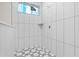 A modern shower with white tile and a geometric patterned floor at 11910 Sw 43Rd Street Road, Ocala, FL 34481