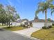 House exterior showcasing a front yard, driveway, and neighboring homes at 1509 Hollyberry Pl, The Villages, FL 32162